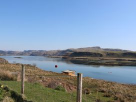 A body of water with hills in the background a small wooden shed a wire fence and buoys in the water at WildLuing in Cullipool Isle Of Luing