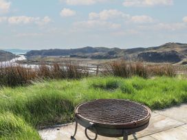 A metal fire pit on a stone patio with grassy land and hills in the background at WildLuing Cullipool Isle Of Luing