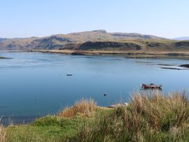 A body of water with two boats and hills in the background at WildLuing Cullipool Isle Of Luing