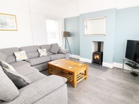 A living room with a grey sectional sofa wooden coffee table a burning stove and a television at 51 Trinity Avenue in Llandudno