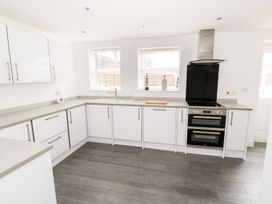 A kitchen with white cabinets gray countertops two windows sink stove and oven at 51 Trinity Avenue in Llandudno