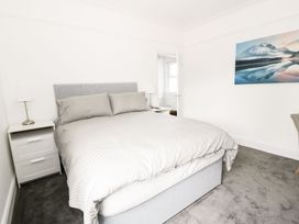 A bedroom with a grey bed and bedside tables with lamps at 51 Trinity Avenue in Llandudno