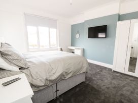 A bedroom with a bed desk wall mirror wardrobe and television at 51 Trinity Avenue in Llandudno