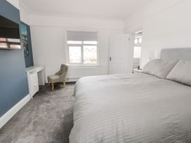 A bedroom with a bed a chair a desk a window and a wall mounted television at 51 Trinity Avenue in Llandudno