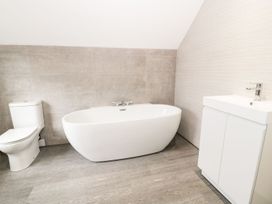 A bathroom with a toilet bathtub and a sink with cabinet at 51 Trinity Avenue in Llandudno