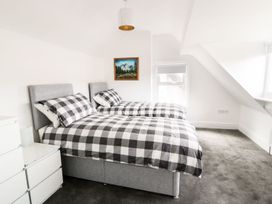 A bedroom with two single beds with checkered bedding a white chest of drawers and a painting on the wall at 51 Trinity Avenue in Llandudno