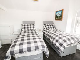A bedroom with two single beds with checkered bedding a dresser and a landscape painting at 51 Trinity Avenue in Llandudno
