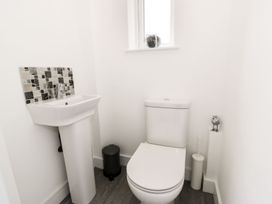A small bathroom with a toilet sink black bin and a window at 51 Trinity Avenue in Llandudno