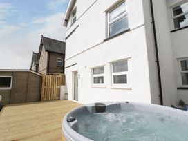 A wooden deck with a hot tub against a white exterior wall of a house at 51 Trinity Avenue in Llandudno