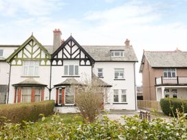A row of three houses with pitched roofs and front gardens at 51 Trinity Avenue in Llandudno