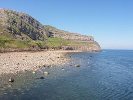 A rocky coastline with cliffs and clear blue water at 51 Trinity Avenue in Llandudno