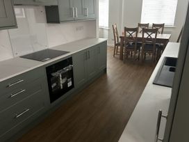 A kitchen with cabinets and a dining table at 40 Gloddaeth View Llandudno
