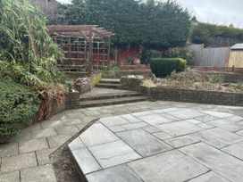 A garden with a patio and steps leading to a trellis at 40 Gloddaeth View Llandudno