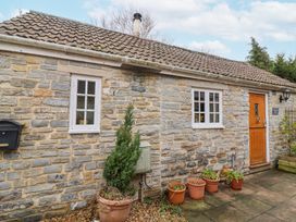 A stone cottage exterior with two white framed windows a wooden door several plant pots and a mailbox at Honeysuckle Cottage in Compton Dundon near Street
