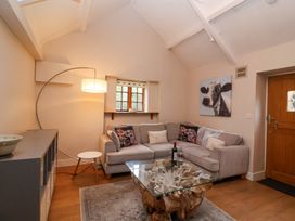 A living room with a sectional sofa glass coffee table and wooden door at Honeysuckle Cottage in Compton Dundon near Street