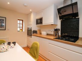 A kitchen with white cabinets wooden countertops gas stove microwave oven and a table with green chairs at Honeysuckle Cottage in Compton Dundon near Street