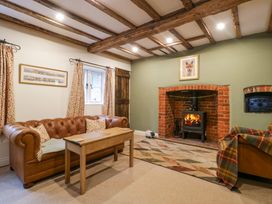 A living room with a leather sofa wooden coffee table fireplace and exposed wooden beams at 2 Loxter Villas in Wellington Heath near Ledbury