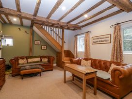 A living room with two leather sofas a wooden table stairs and exposed wooden ceiling beams at 2 Loxter Villas Wellington Heath near Ledbury