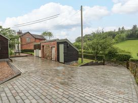 An outdoor area with houses, a paved driveway, and trees at 2 Loxter Villas in Wellington Heath near Ledbury