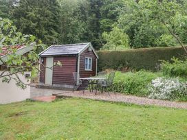 A shed with chairs and a table on a path surrounded by grass at 2 Loxter Villas Wellington Heath near Ledbury