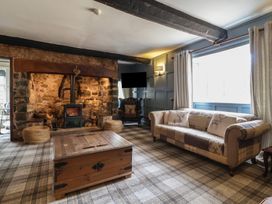 A living room with a stone fireplace wooden coffee table patterned sofa and armchair at Dragon House in Bilbrook near Minehead