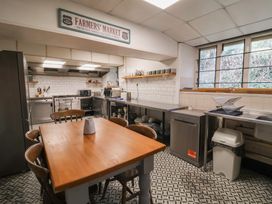 A kitchen with a wooden table and chairs stainless steel counters and appliances at Dragon House in Bilbrook near Minehead