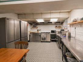 A kitchen with stainless steel appliances and counters and wooden table and chairs at Dragon House in Bilbrook near Minehead