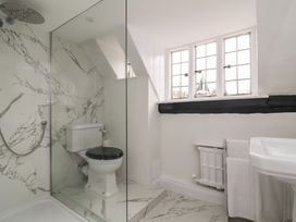 A bathroom with a shower, toilet, sink, window, and radiator with towels at Dragon House in Bilbrook near Minehead
