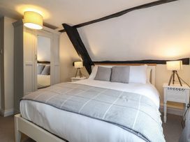 A bedroom with a bed grey blanket pillows two bedside tables lamps and a wardrobe with mirror at Dragon House in Bilbrook near Minehead