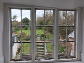 A garden with grass stairs and shrubs viewed through a window at Dragon House in Bilbrook near Minehead
