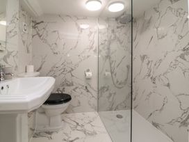 A bathroom with a sink toilet and a walk in shower with marble tiled walls and floor at Dragon House in Bilbrook near Minehead
