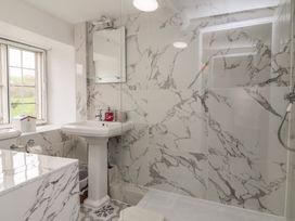 A bathroom with a pedestal sink mirror toilet window and a shower area with marble tiles at Dragon House in Bilbrook near Minehead