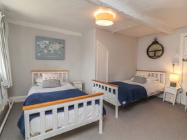 A bedroom with two single beds a nightstand with a lamp and a world map on the wall at Dragon House in Bilbrook near Minehead