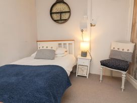 A bedroom with a single bed side table with lamp and a chair with cushions at Dragon House in Bilbrook near Minehead