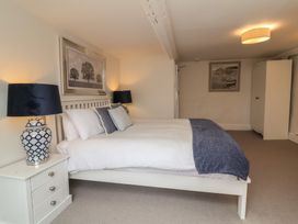 A bedroom with a white bed and blue pillows next to a white nightstand with a blue lamp at Dragon House in Bilbrook near Minehead