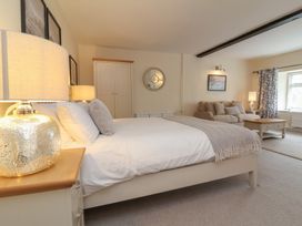 A bedroom with a bed a sofa a wardrobe and a window with curtains at Dragon House in Bilbrook near Minehead