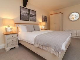 A bedroom with a double bed bedside tables lamps wardrobe and framed photos at Dragon House in Bilbrook near Minehead