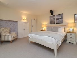 A bedroom with a bed and two bedside tables with lamps and a striped armchair at Dragon House in Bilbrook near Minehead