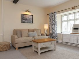 A living room with a beige sofa coffee table lamp and window at Dragon House in Bilbrook near Minehead