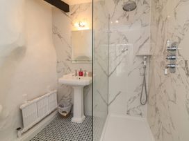 A bathroom with a pedestal sink a mirror a trash bin a radiator and a walk in shower at Dragon House in Bilbrook near Minehead