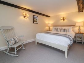 A bedroom with a bed bedside tables lamps wall sconces and a rocking chair at Dragon House in Bilbrook near Minehead