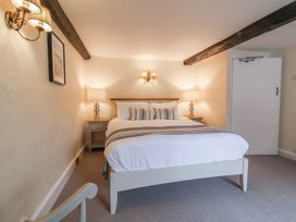 A bedroom with a double bed two bedside tables with lamps exposed wooden ceiling beams and a wall lamp at Dragon House in Bilbrook near Minehead