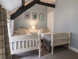 A bedroom with two single beds a nightstand with a lamp three framed bird pictures on the wall and exposed wooden beams at Dragon House in Bilbrook near Minehead