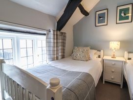 A bedroom with two single beds a nightstand with a lamp and bird pictures on the wall at Dragon House in Bilbrook near Minehead