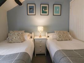 A bedroom with two single beds a nightstand with a lamp and bird pictures on the wall at Dragon House in Bilbrook near Minehead