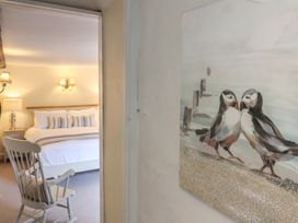 A bedroom with a bed a rocking chair and a painting of two birds at Dragon House in Bilbrook near Minehead