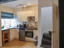 A kitchen with white cabinets a small refrigerator oven microwave and toaster next to a staircase at Dragon House in Bilbrook near Minehead
