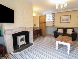 A living room with a stone fireplace a leather sofa a wooden coffee table and a television at Dragon House in Bilbrook near Minehead