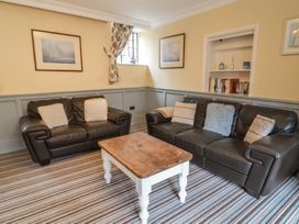 A sitting room with two brown leather sofas a wooden coffee table striped carpet and framed pictures at Dragon House in Bilbrook near Minehead
