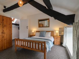 A bedroom with a wooden bed and nightstands with lamps and a wardrobe at Dragon House in Bilbrook near Minehead